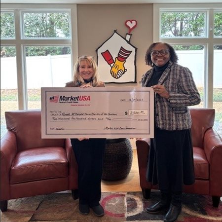 Ladies holding large gift check to McDonald House